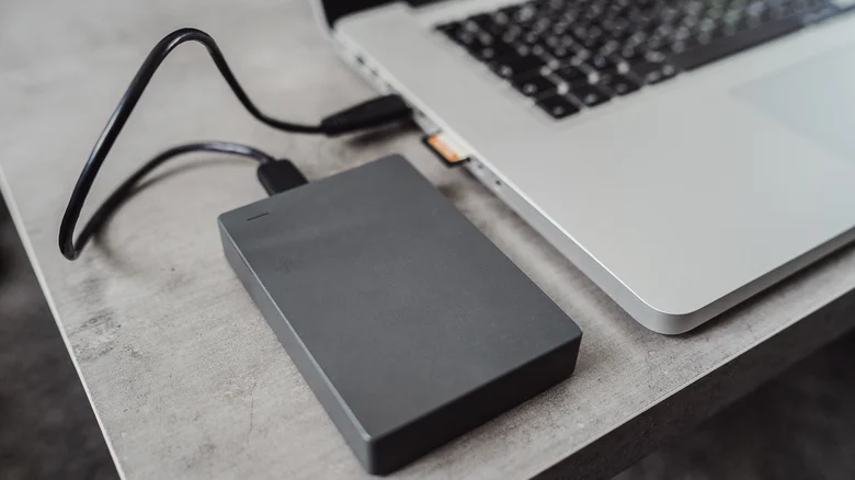 An external hard drive plugged into the side of a laptop.
