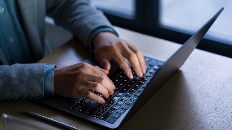 Person typing on a black laptop with both hands.