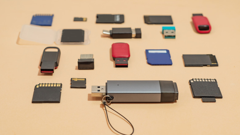 A bunch of USB drives and SD cards on a tan surface.