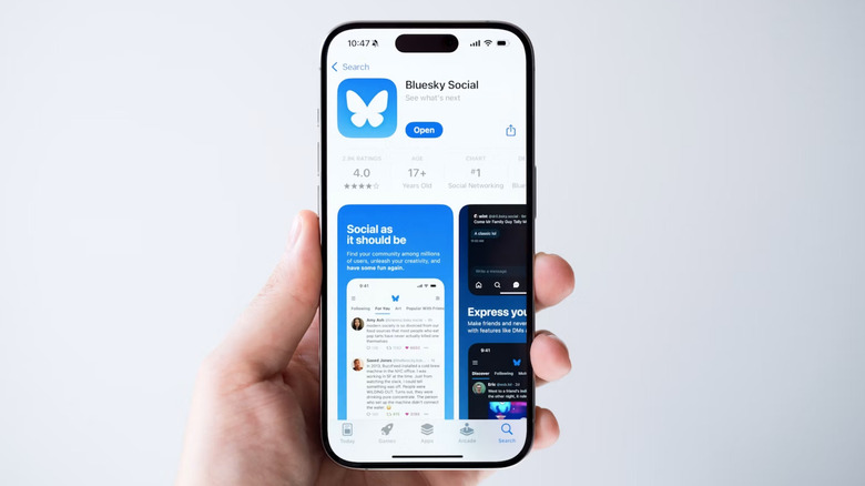 A hand holding a smartphone showing Bluesky.