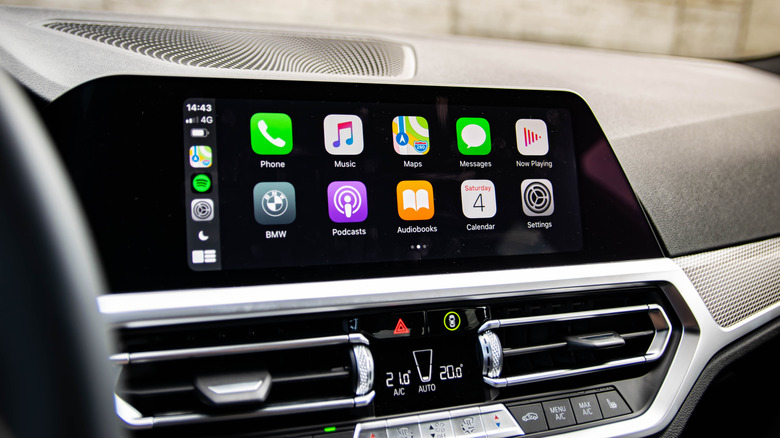 Apple CarPlay interface displayed on a BMW infotainment screen with apps for Phone, Music, Maps, Messages, Podcasts and Settings.