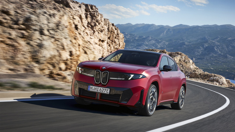 BMW's new iX4 in Euro trim shown in red on a twisty mountain road