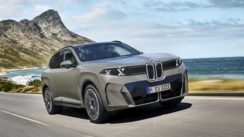 A grey BMW iX5 is shown on an arid coastal road