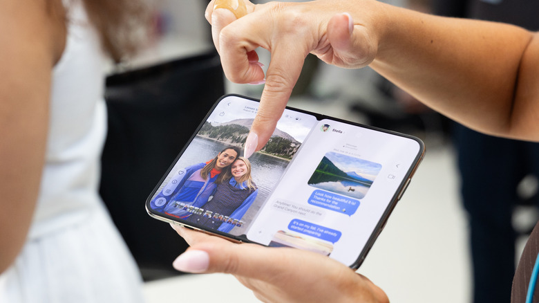 A person holding an iPhone Duo showing two images on either side of the screen.