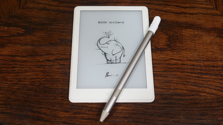 A white Boox Go 6 (Gen )) ereader is pictured on a dark wooden table with a silver and white stylus resting on top of it.