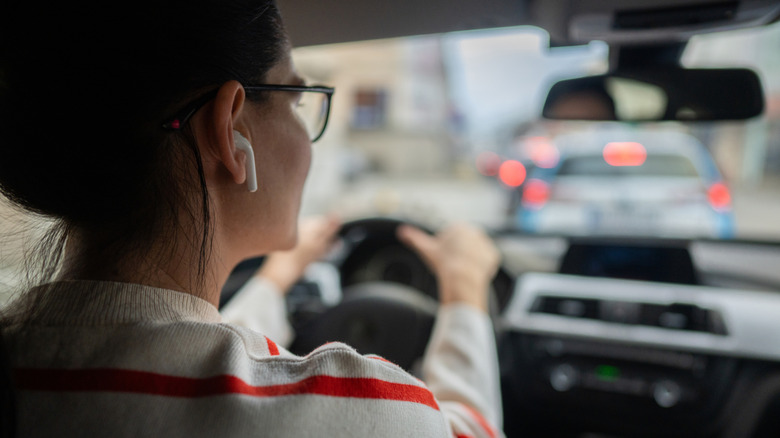 A woman behind the wheel with an earbud in