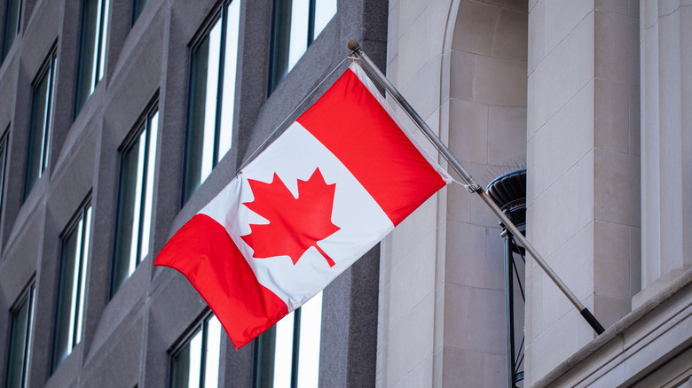 The Canadian flag hanging off a building.