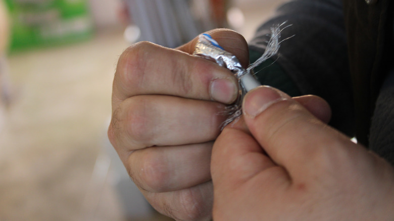Hands peeling back foil and braided shielding from a cable.
