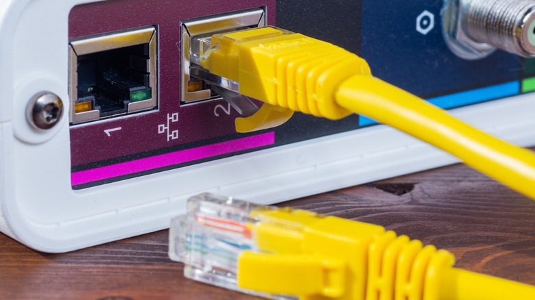 Yellow Ethernet cable plugged into a network port with another Ethernet cable in the foreground.