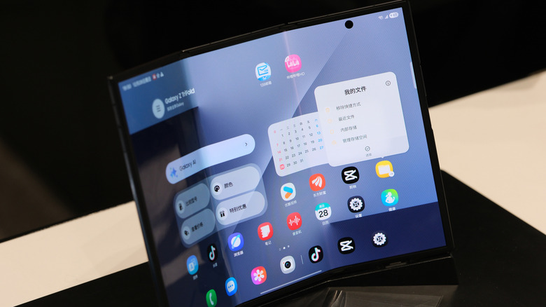 A tri-fold phone on display, showing its home screen with various apps and widgets.