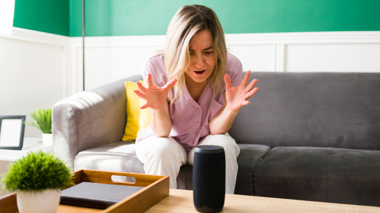 A woman looking frustrated at a Bluetooth speaker
