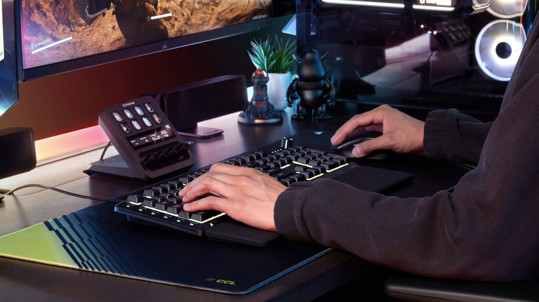 A hand on a mouse as a person types on a keyboard.