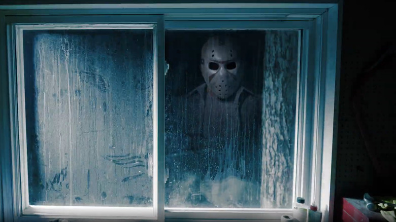 A reflection of Friday the 13th villain Jason Voorhees and his iconic hockey mask in a filthy window
