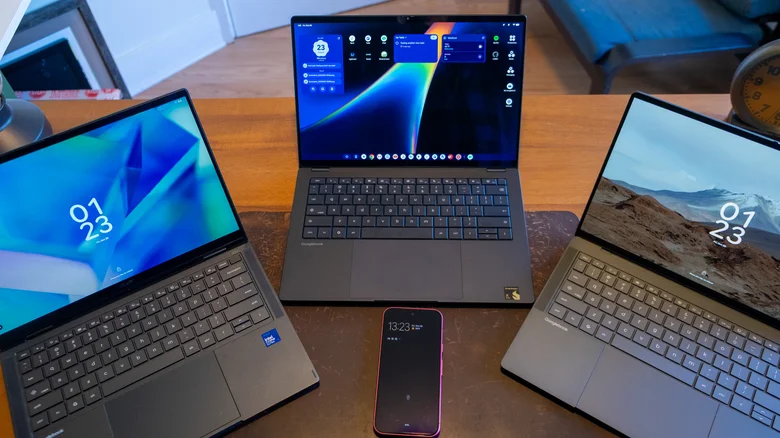 Three Googlebooks sitting on a desk with a Pixel 11 phone.