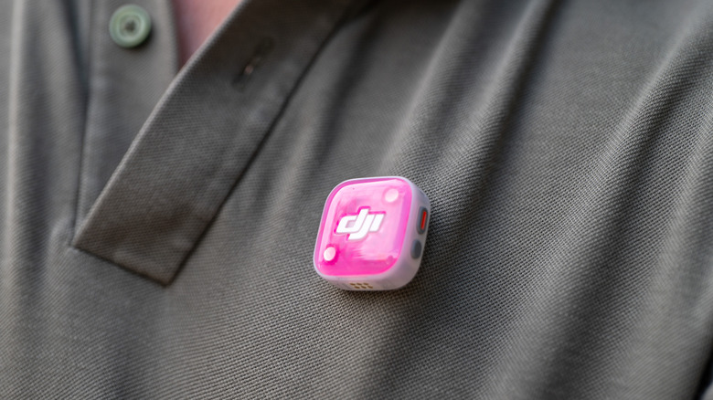 The DJI Mic Mini 2S transmitter is shown magnetically attached to subject's shirt with pink magnetic cover