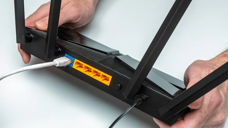 The rear view of a gaming router, showing an Ethernet cable connected to the WAN port, along with four spare ports.