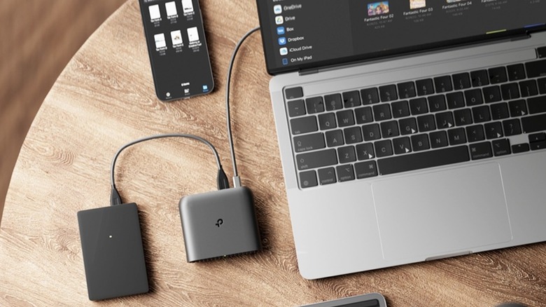 TP-Link travel router connected to a laptop, next to a smartphone.