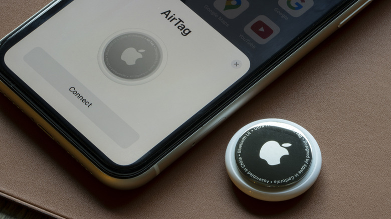 An AirTag next to an iPhone, being paired with the phone.