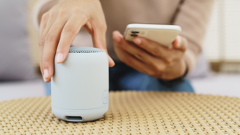 A person connects their phone to a Bluetooth speaker.