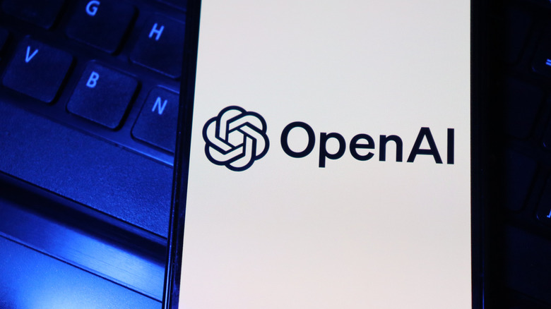 A smartphone displaying the OpenAI logo on a keyboard.