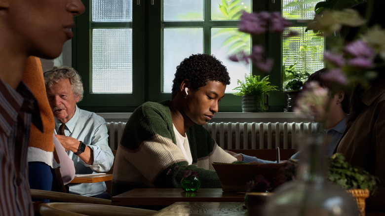 A person in a busy cafe wearing the AirPods 5.