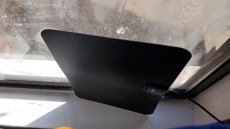 An indoor TV antenna placed beside a window.