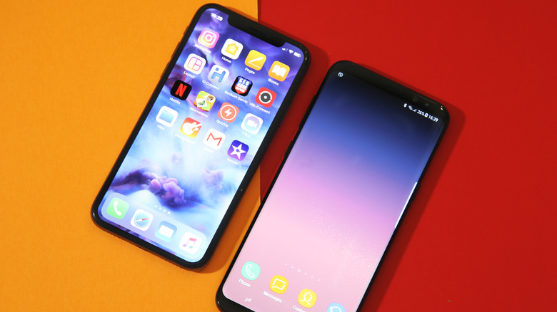 iPhone X and Samsung S8+ laying side-by-side.