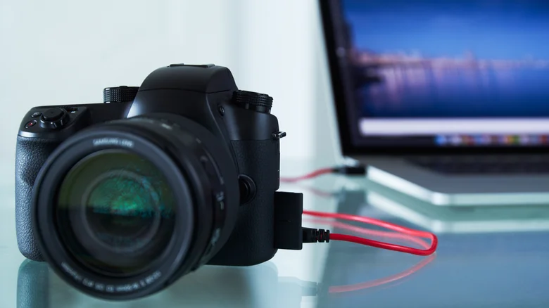 DSLR camera connected by a cable beside a laptop.