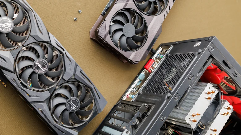 Two video cards sit beside a desktop PC they are being installed into.