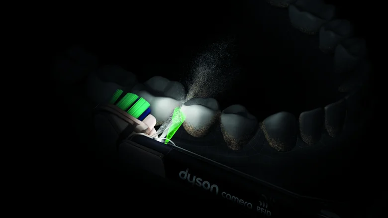 A close up of the Dyson CameraJet squirting water into the gap between teeth.