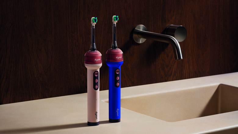A pair of Dyson CameraJet toothbrushes standing next to a sink.