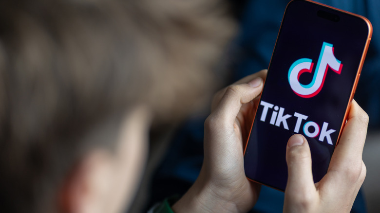 A person holding a phone with the TikTok logo displayed.