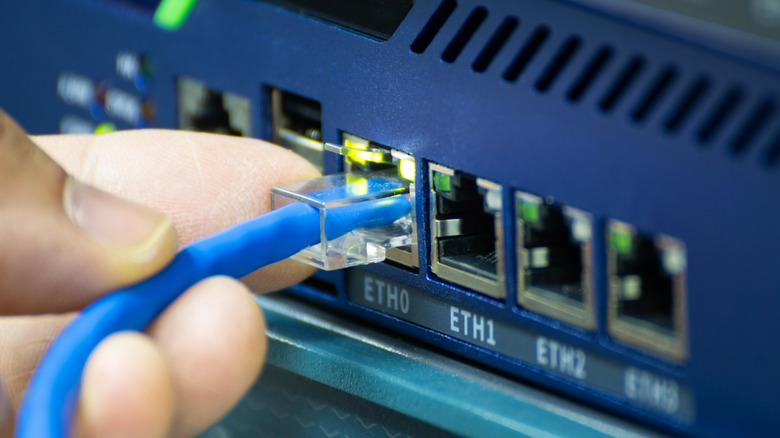 Close up of a hand plugging in an Ethernet cable into a switch