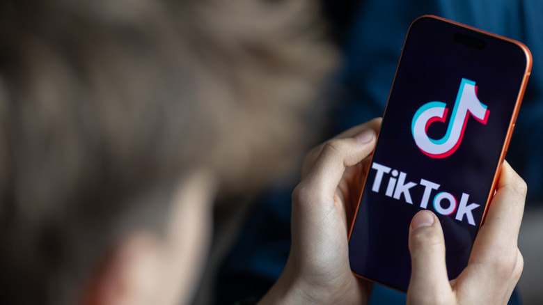 A boy with the TikTok logo on his smartphone.