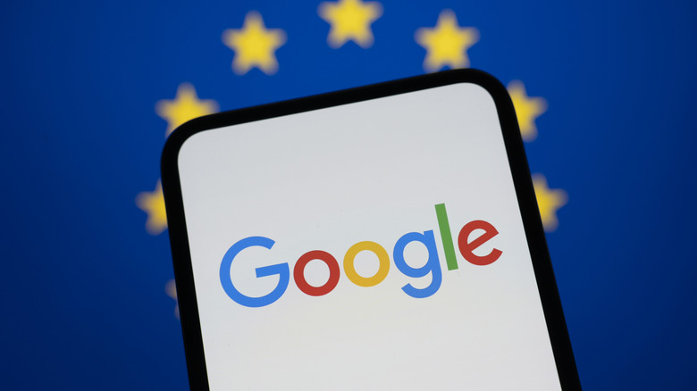 A stock photo showing the Google logo on a phone against the European flag in blue and gold