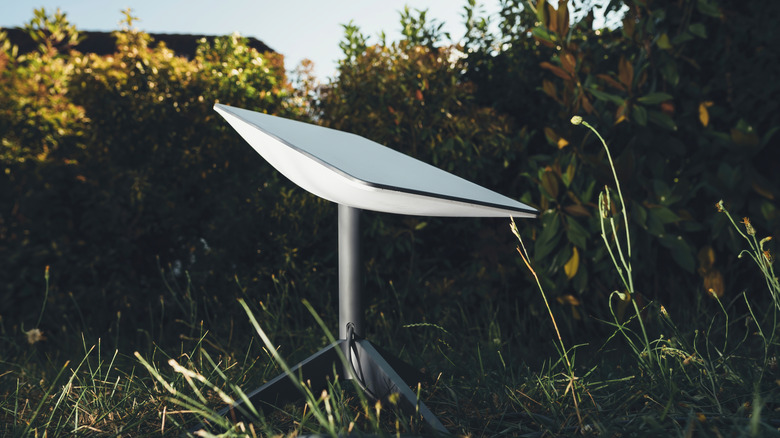 Starlink dish on the ground in a yard searching for SpaceX satellites.