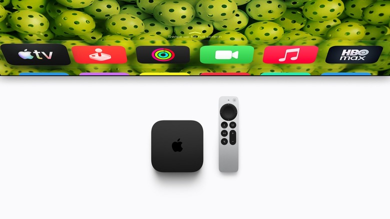 Apple TV 4K set-top box and Siri remote in front of a TV that displays the device's interface.