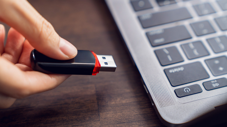 Woman inserting thumb drive into laptop port
