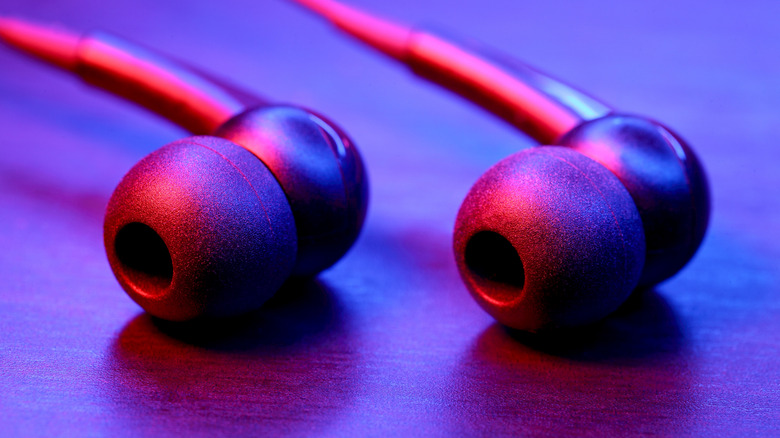 Wired earbuds in red and blue lighting.