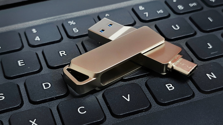 A dual USB flash drive with USB-A and USB-C connectors, on top of a keyboard.