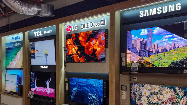 A row of demo TVs from LG, Samsung, and more in a retail shop.