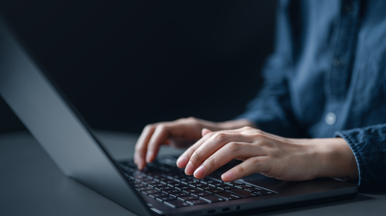 A person typing on a laptop keyboard.