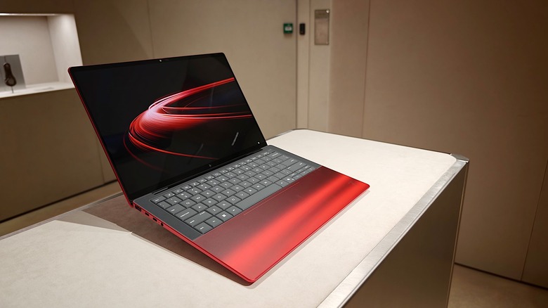 Ferrari and HP's new laptop collaboration, positioned in front of Ferrari car parts and objects.