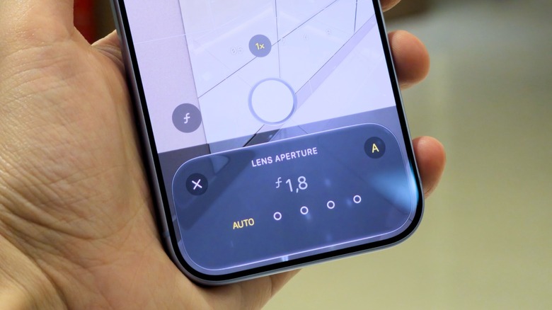 Hand holding an iPhone, showing aperture control on the iPhone 18 Pro.