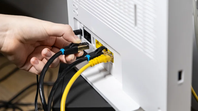 Hand plugging ethernet cable into a router with multiple connections.