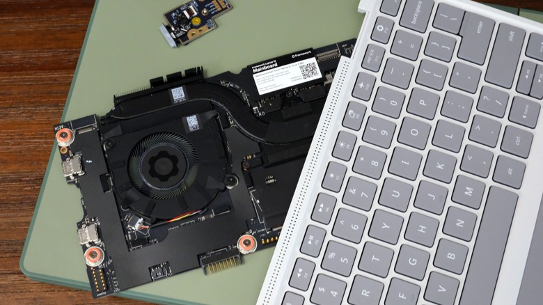 Framework Laptop 12 on a table, on top of which is its mainboard, fingerprint reader and input cover.