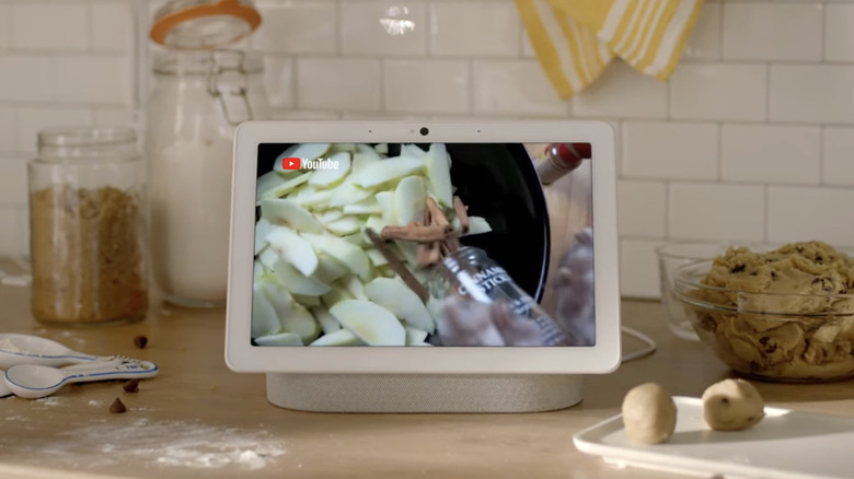 A smart display on top of a counter, surrounded by cooking ingredients.