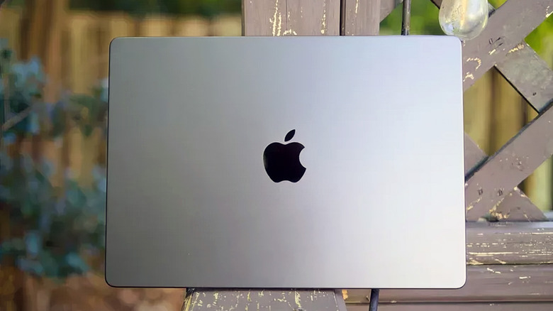 The back of a MacBook Pro sitting on an outdoor bench.