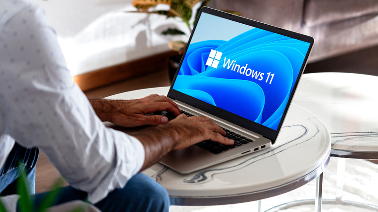Person using Windows 11 laptop on a table.