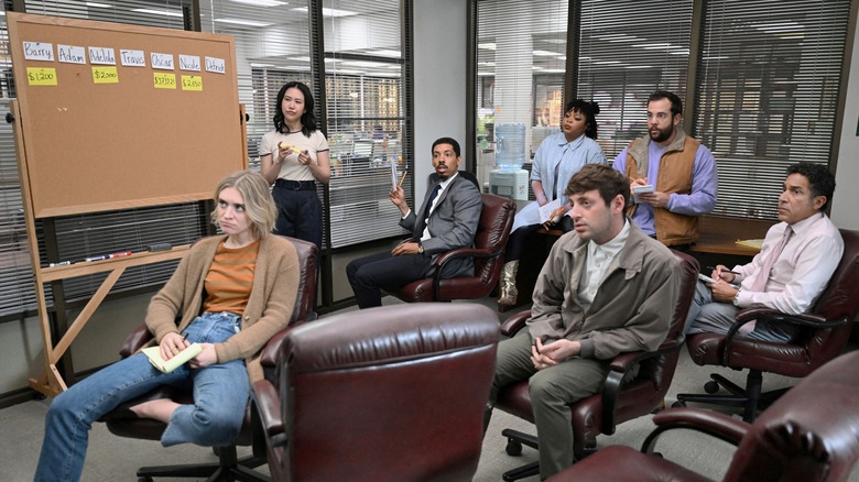 The Paper's staff sit in a drab conference room with looks of circumspection, shock, confusion, and boredom.